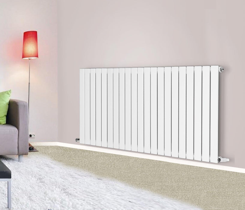 A horizontal designer radiator with flat panels, colored in white, Size 600*1428 mounted on a wall in a room with a modern decor. The radiator features a sleek, contemporary design with vertical bars.